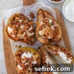 Cooked pears on wooden board topped with plain yoghurt and granola. One pear cut in half.