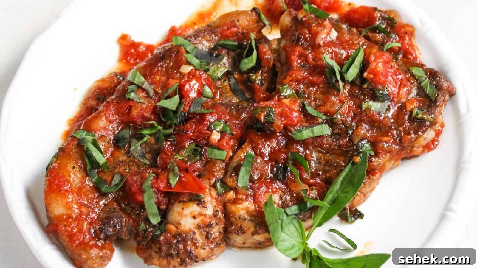 Fried steak topped with a chunky tomato and basil sauce, served on a white plate.