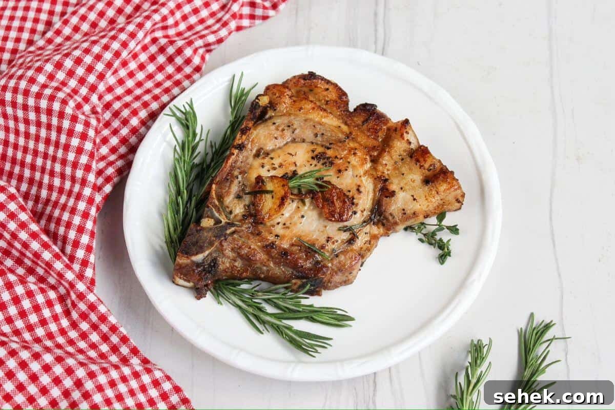 Pork chops on a plate with rosemary sprigs.