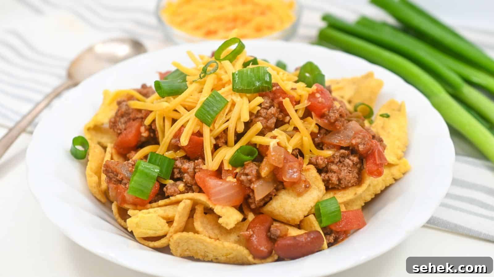 A plate of Fritos topped with ground beef, cheese, tomatoes, beans, and green onions.