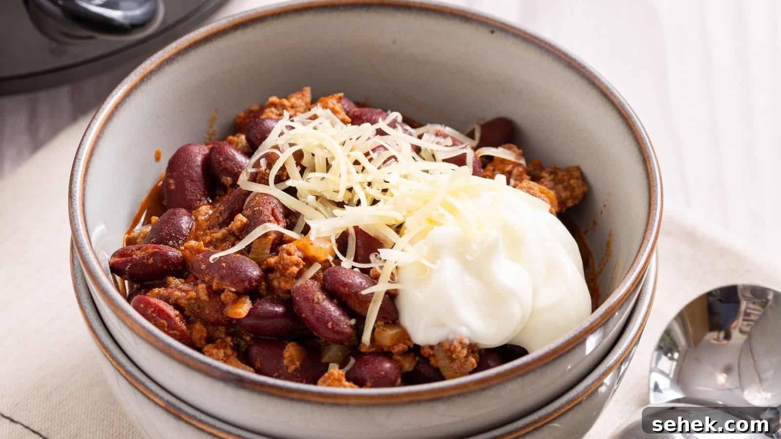 Crock Pot Chili served in two white bowls with spoon.