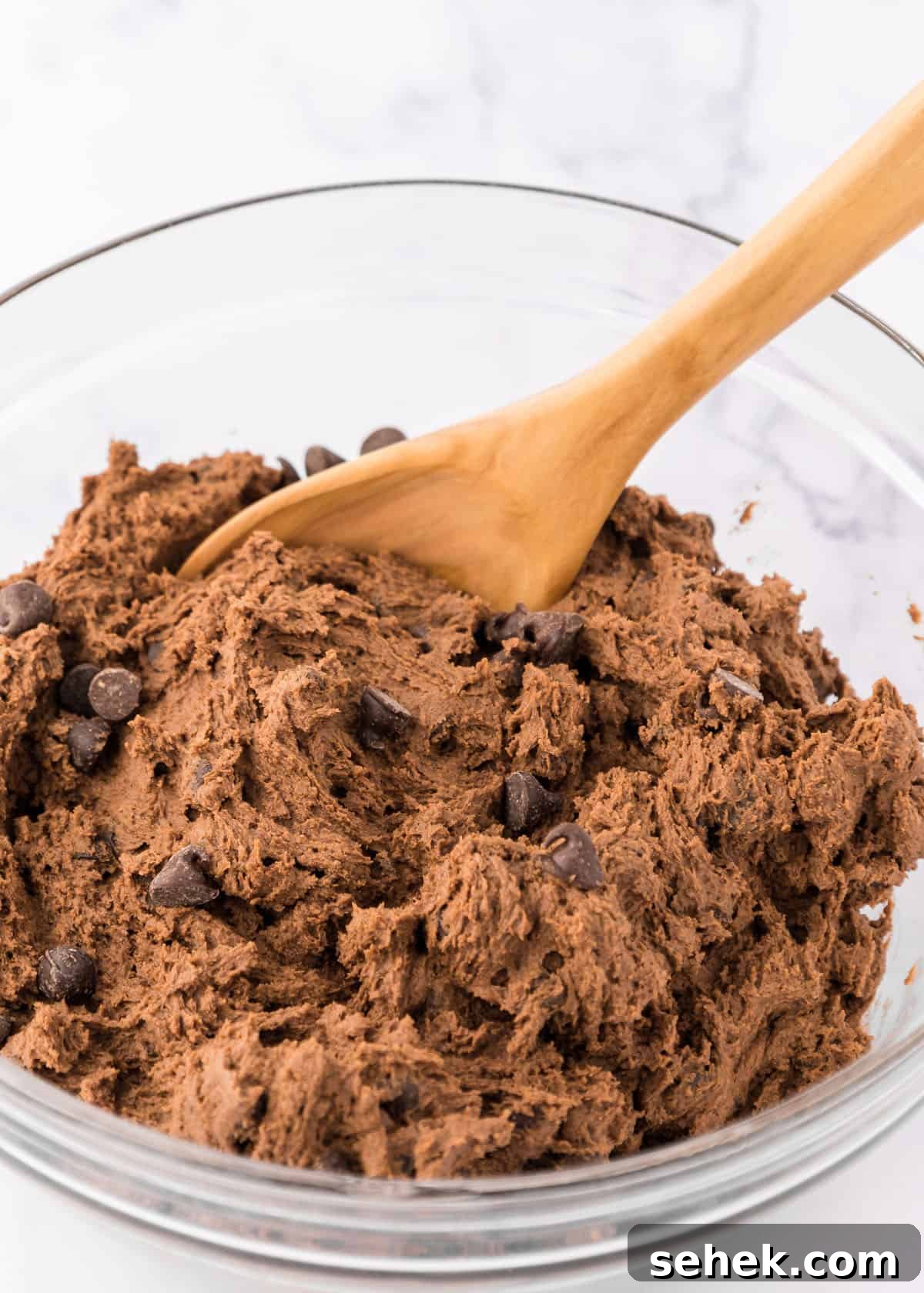 Ultimate Double Chocolate Cookies Recipe for Rich, Fudgy Results 5 Double chocolate chip cookie dough in a bowl with a wooden spoon.