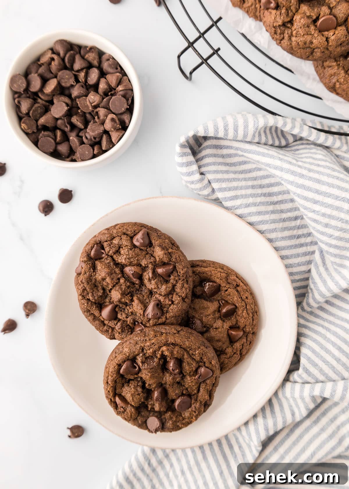 Ultimate Double Chocolate Cookies Recipe for Rich, Fudgy Results 9 Double chocolate chip cookies on a plate next to a bowl of chocolate chips.