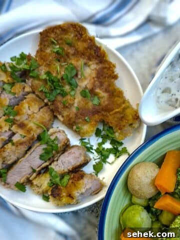 Crumbed pork chops on a plate, garnished with parsley.