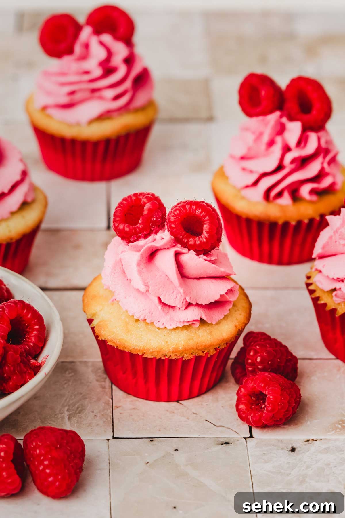 Silky Raspberry Frosting Recipe for Cakes and Cupcakes 3 cupcakes with raspberry mascarpone frosting on a table