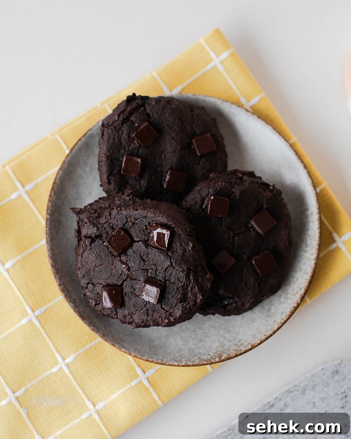 Fudgy Flourless Black Bean Cookies — Vegan Chocolate Treats 9 Plate of baked black bean cookies with chocolate chunks on a yellow cloth