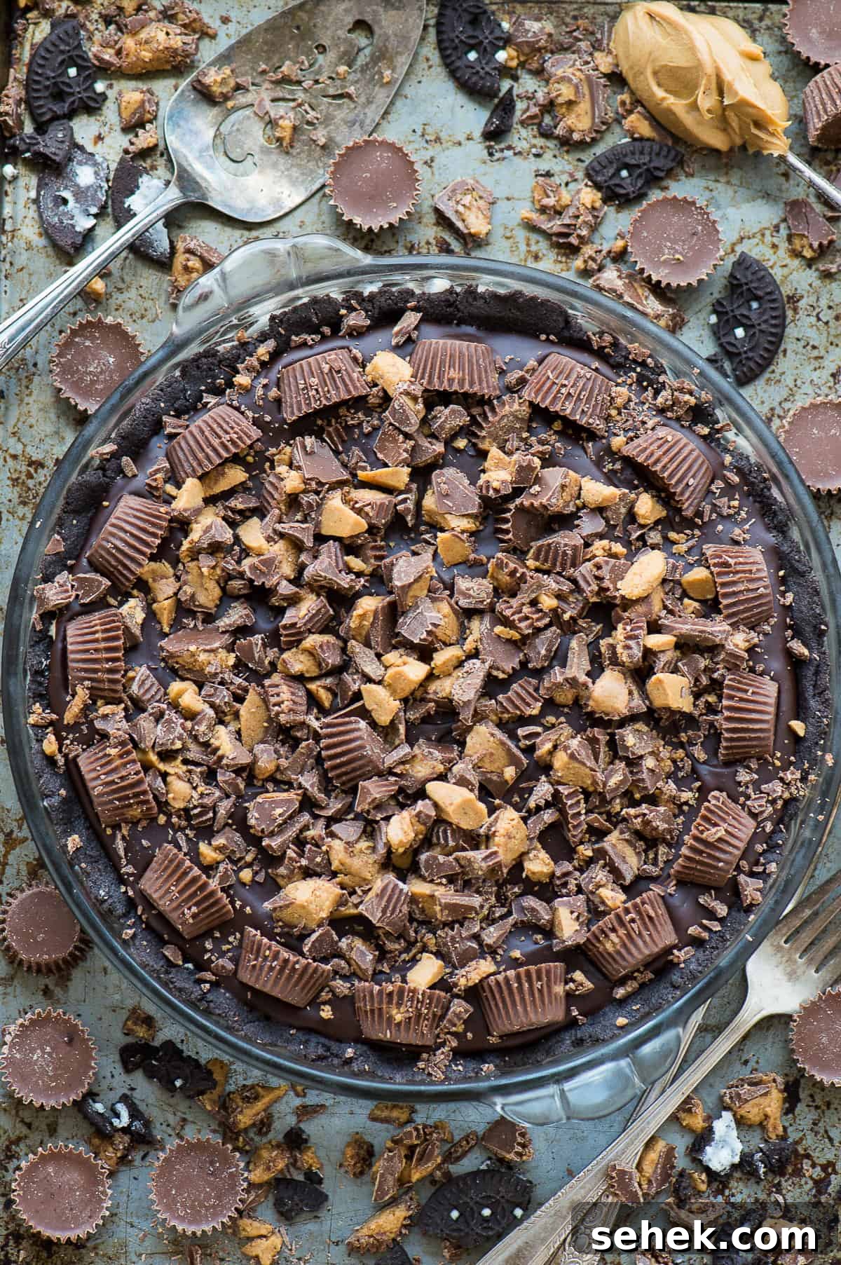chocolate peanut butter pie with reese's cups in glass pie pan on metal background