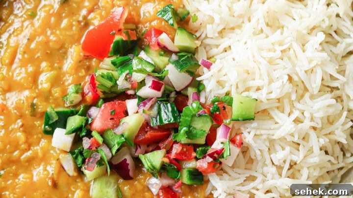 A bowl with rice and Masoor Dal topped with crunchy vegetables.