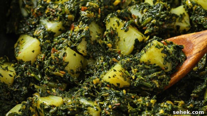 Close up of Aloo Palak in a skillet with a wooden spoon.