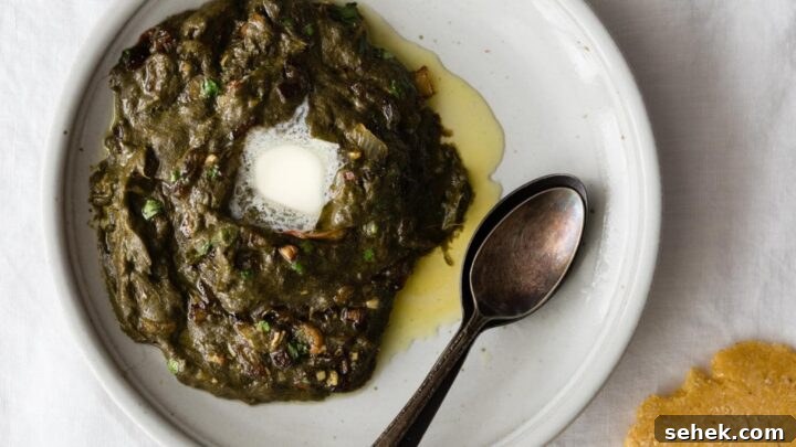 Sarson Ka Saag with a dollop of butter on a plate with spoons and makai ki roti on the side