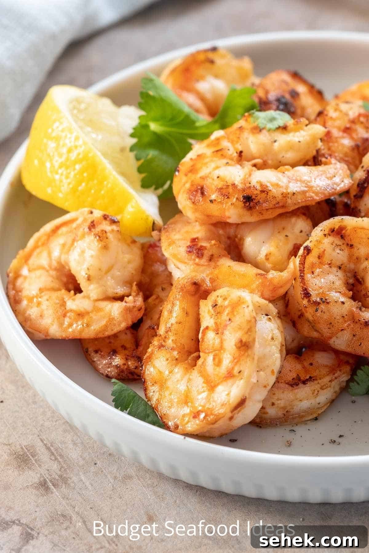 Affordable Seafood Recipes for Flavorful Weeknight Meals 2 Cooked seasoned shrimp in a white, round dish with a slice of lemon.
