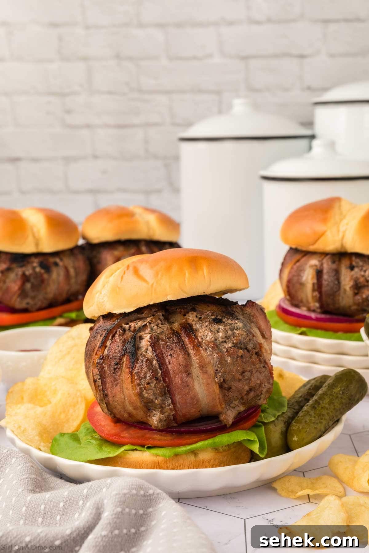 Bacon-Wrapped Burger Recipe: Juicy Grilled Bacon Burger Guide 14 Bacon wrapped burger on a plate with pickles and potato chips
