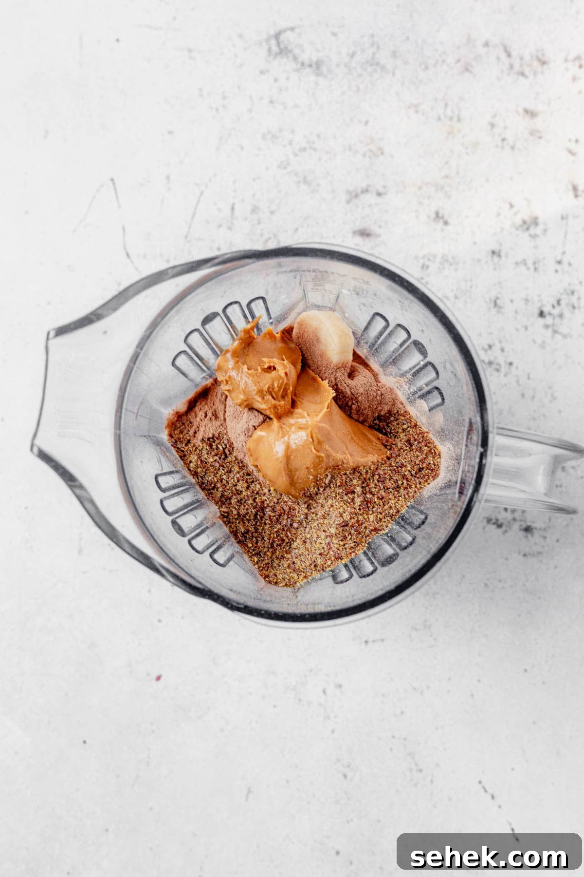 Chocolate Peanut Butter Protein Shake for Muscle Recovery 4 chocolate protein powder, milk, frozen bananas, and peanut butter in a blender.
