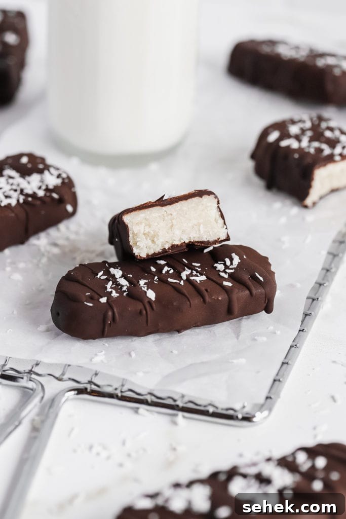 Vegan Coconut Bounty Bars Recipe — 6 Ingredients, No Bake 2 side view of gluten free and vegan coconut bounty bars on parchment paper with a glass of milk