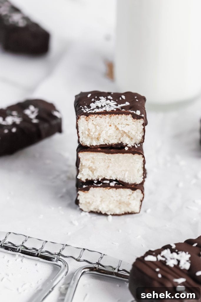 Vegan Coconut Bounty Bars Recipe — 6 Ingredients, No Bake 4 a stack of soft and creamy homemade coconut candy bars with a glass of milk