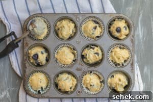 Lemon-Infused Blueberry Muffins Recipe 12 muffin batter being scooped into a muffin tin