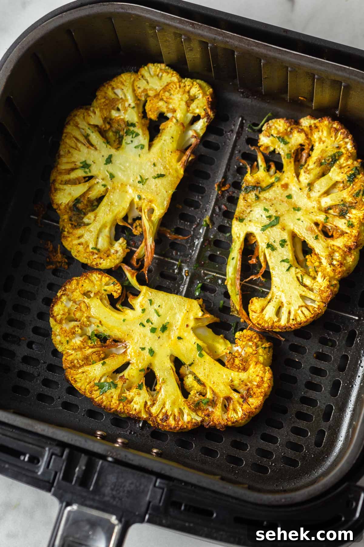 Crispy Air Fryer Cauliflower Steaks with Garlic Herb Sauce 11 air fried cauliflower steaks in the air fryer basket.