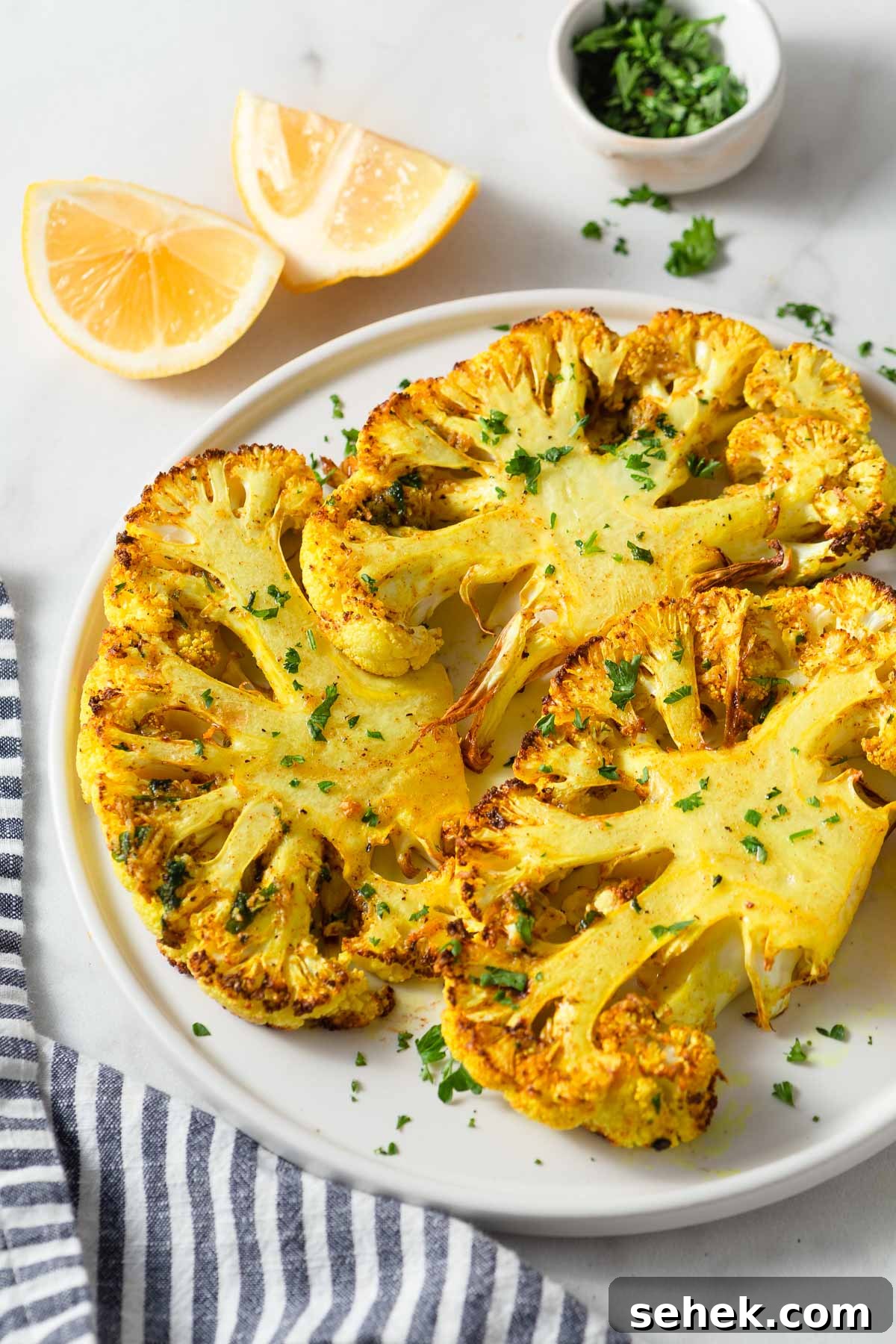 Crispy Air Fryer Cauliflower Steaks with Garlic Herb Sauce 12 air fried cauliflower steaks on a plate.