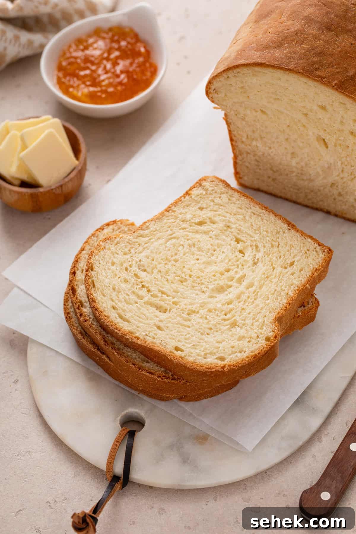 Slices of potato bread on a cutting board next to butter and jam.