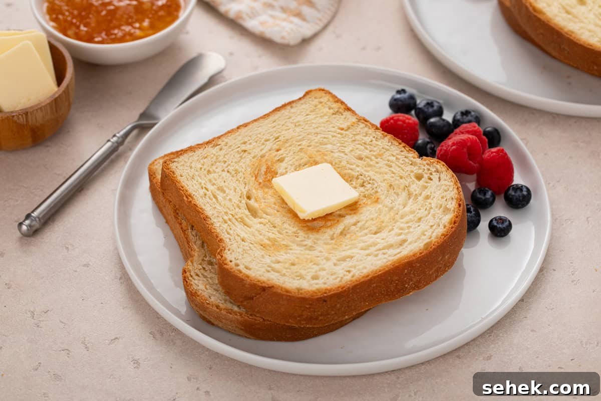 White plate with two slices of toasted potato bread next to fresh berries.