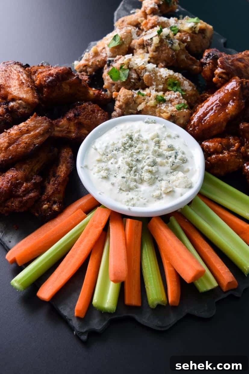 Crispy Air Fryer Wings for Game Day 3 Air Fryer Game Day Wings in three flavors served on black platter with blue cheese celery and carrots up close view