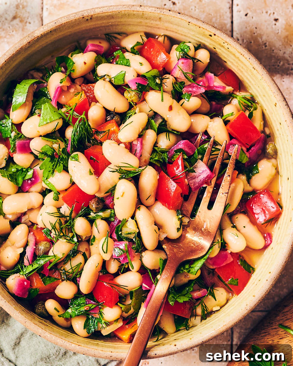 Tuscan Bean Salad with Tomatoes, Olives & Fresh Herbs 7 A bowl of easy Cannellini Bean Salad with a fork.