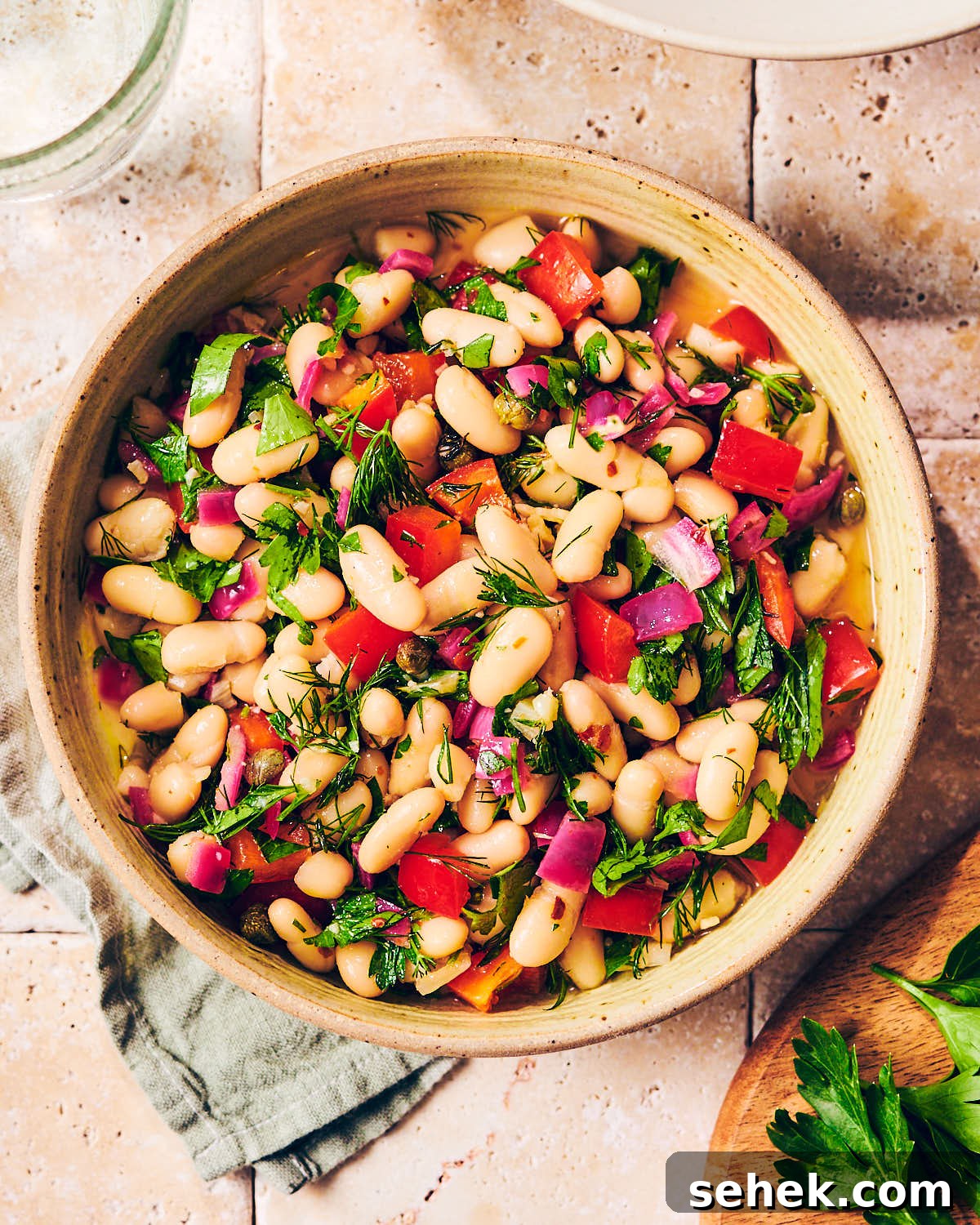 Tuscan Bean Salad with Tomatoes, Olives & Fresh Herbs 9 Tuscan Bean Salad in a bowl serving bowl with a green napkin.