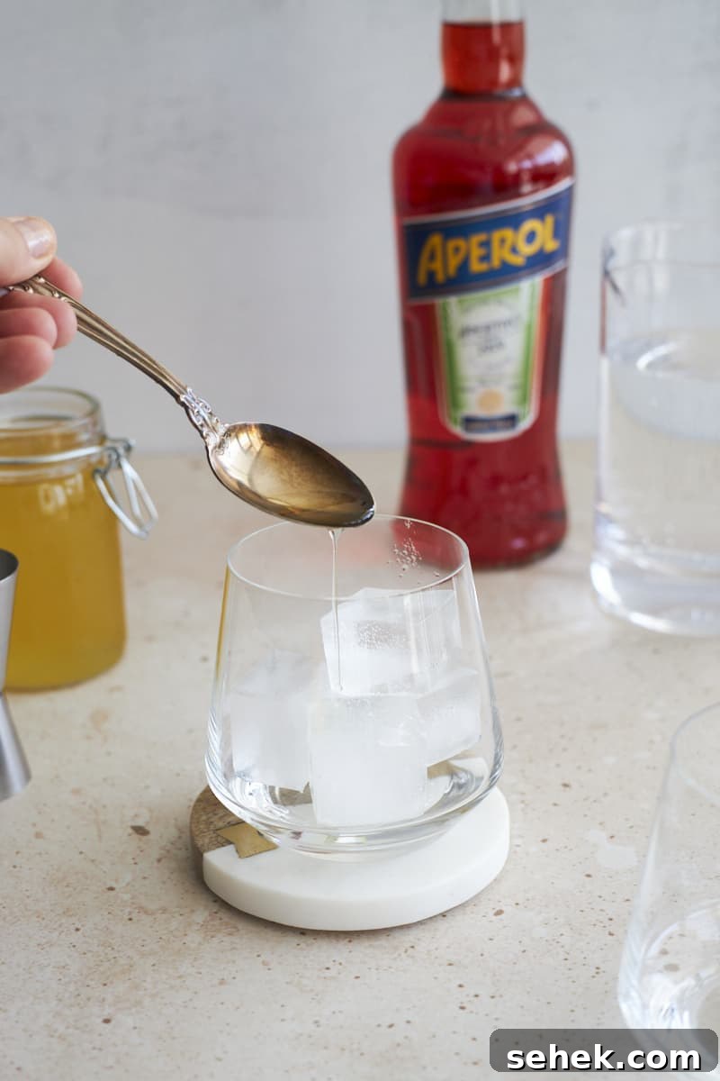 Aperol Soda Cocktail Recipe: Refreshing Italian Spritz Alternative 5 Simple syrup being poured into the cocktail glass.