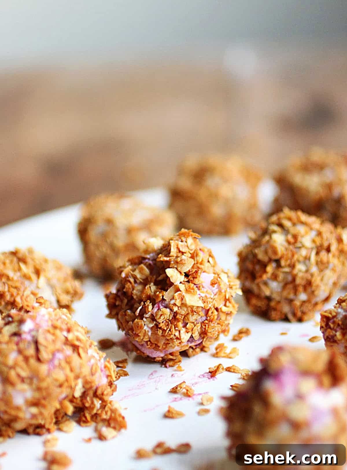 Ice Cream–Filled Granola Truffles: No-Bake Dessert Bites 2 Ice cream truffles covered in granola on white plate.