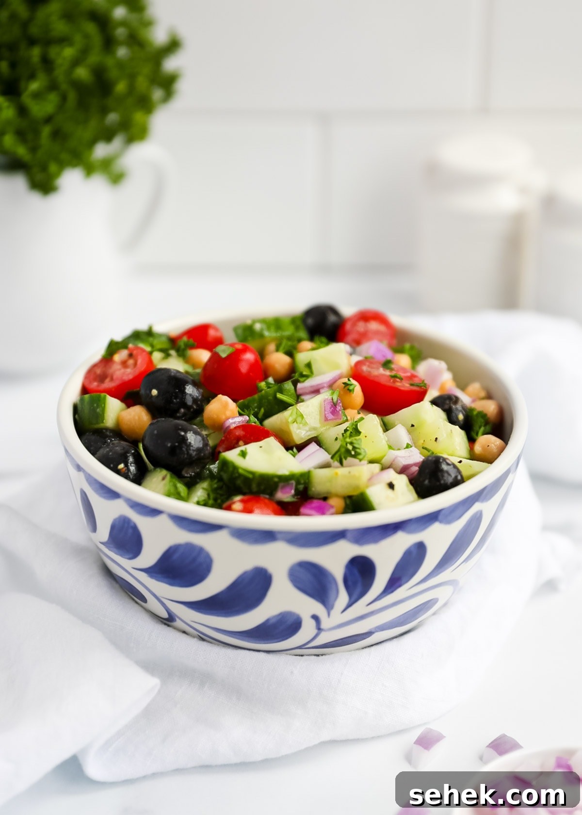 Classic Greek Cucumber Salad with Feta and Olives 2 A bowl of cucumber salad with fresh vegetables, chickpeas, olives, and fresh herbs