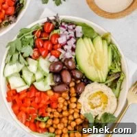 Mediterranean salad in shallow salad bowl with side of tahini dressing.