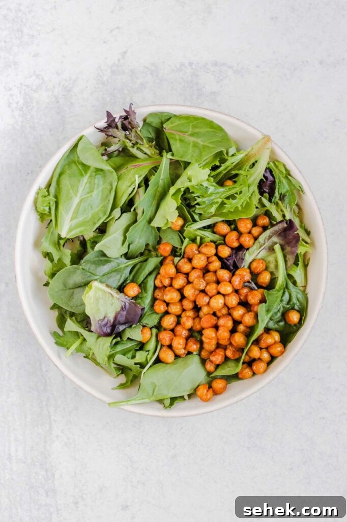 Mixed greens and roasted chickpeas in a salad bowl.