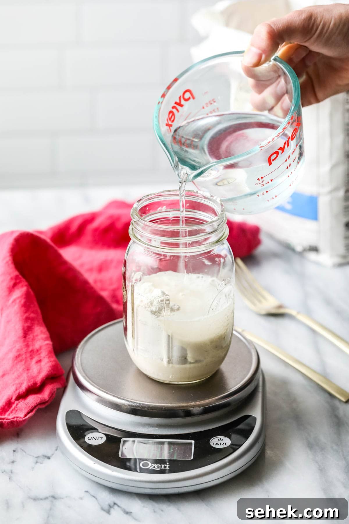 Sourdough Starter Care: How to Feed, Store, and Revive Yours 4 pouring water into sourdough starter
