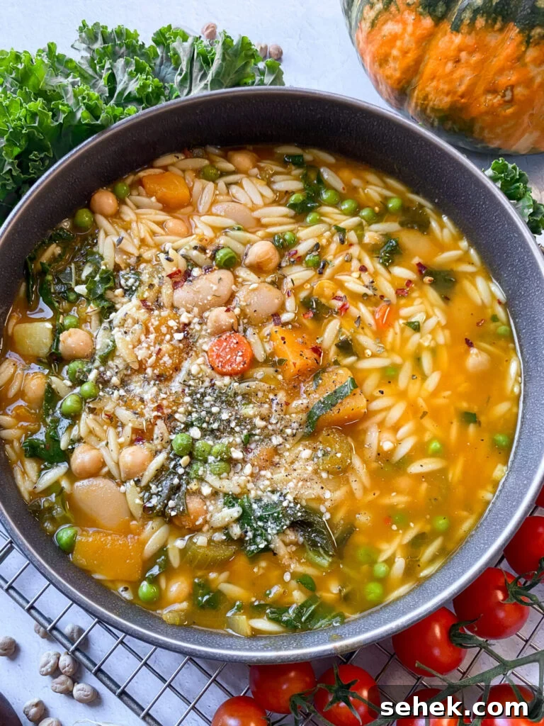 overhead view of a bowl of orzo and kale stew served with fresh herbs.