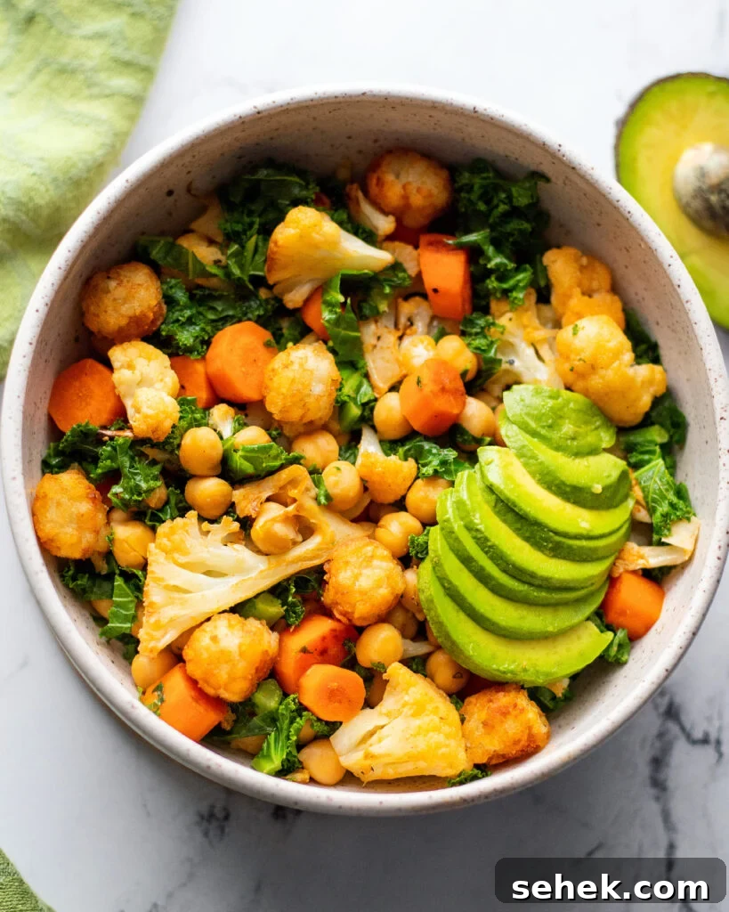 healthy savory vegan breakfast bowl with chickpeas, cauliflower, kale, carrots, and avocado in a white bowl.