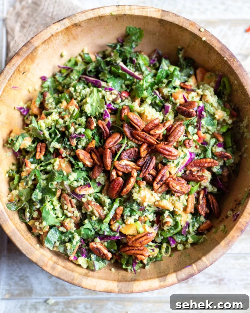 Tropical Kale and Quinoa Salad with pecans, papaya, and quinoa in a wooden serving bowl.