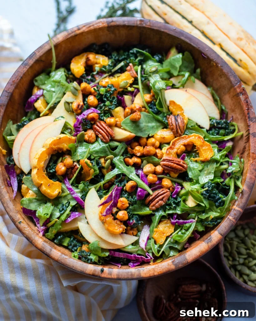 Autumn Kale Salad with arugula, apple, pecans, and chickpeas in a wooden serving bowl.