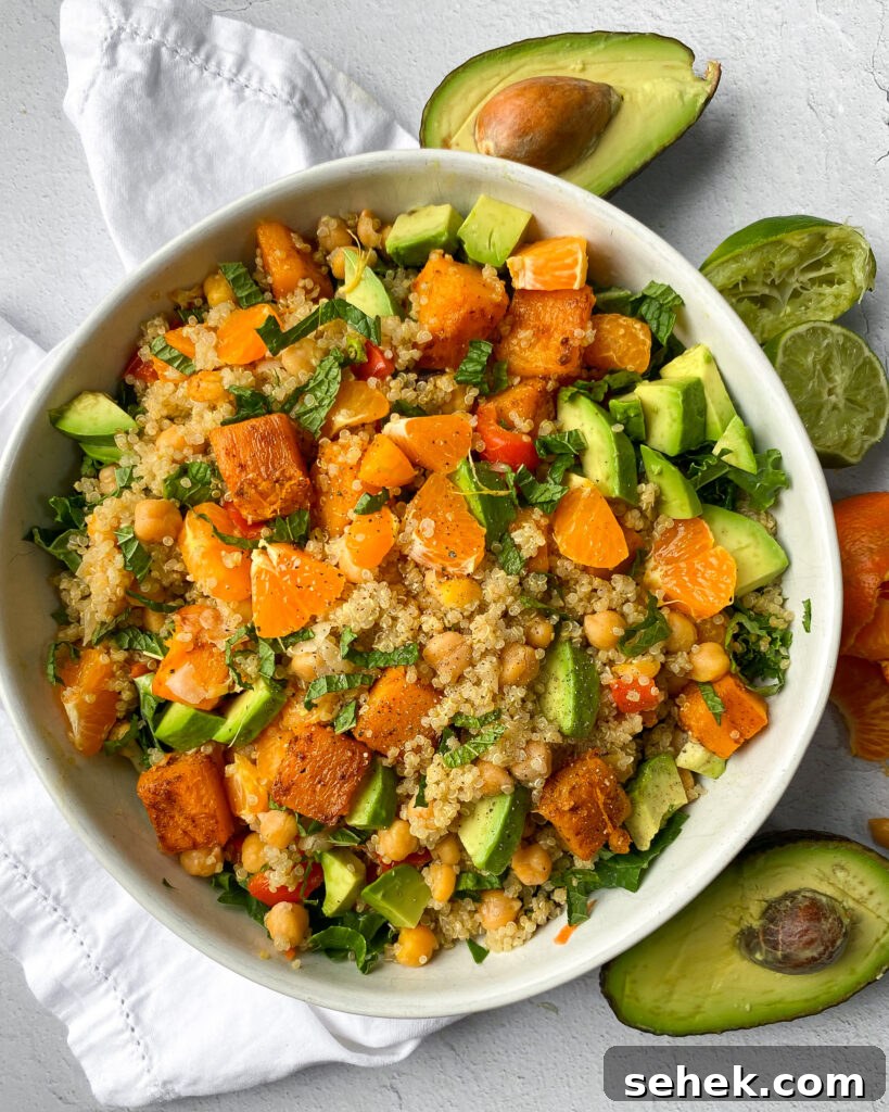 overhead view of a white bowl with a mandarin quinoa salad with butternut squash, avocado, and kale.