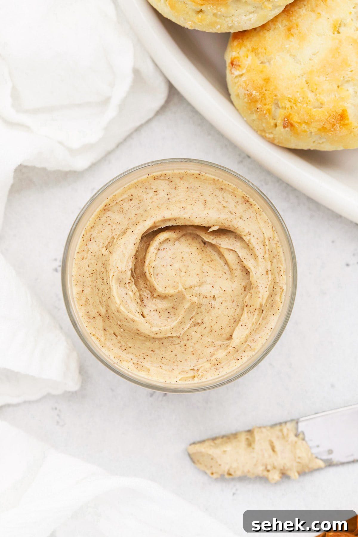 Whipped Honey Butter with Cinnamon — Fluffy Spread Recipe 2 Overhead view of whipped honey butter in a small glass jar with gluten-free biscuits in the background