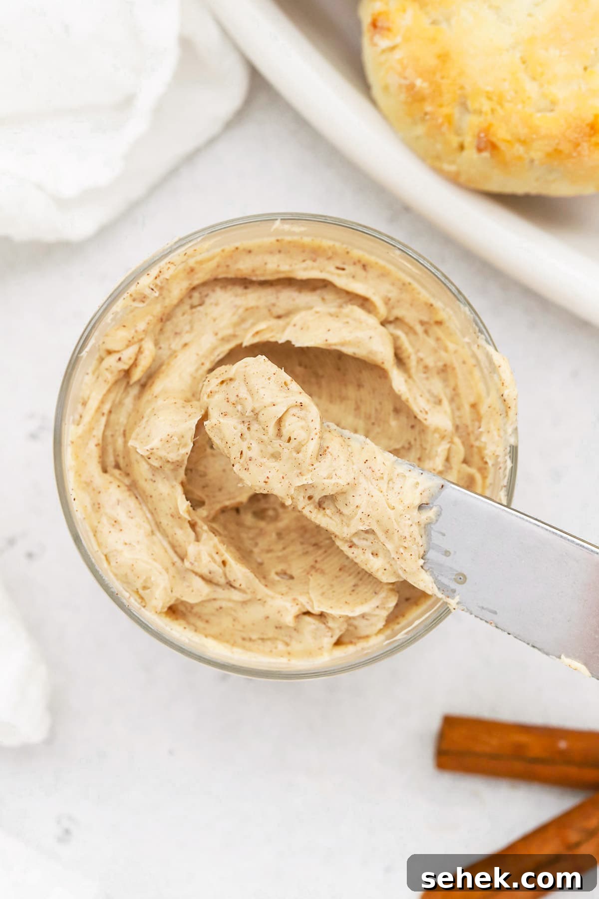 Whipped Honey Butter with Cinnamon — Fluffy Spread Recipe 12 Overhead view of whipped honey butter in a small glass jar with gluten-free biscuits in the background