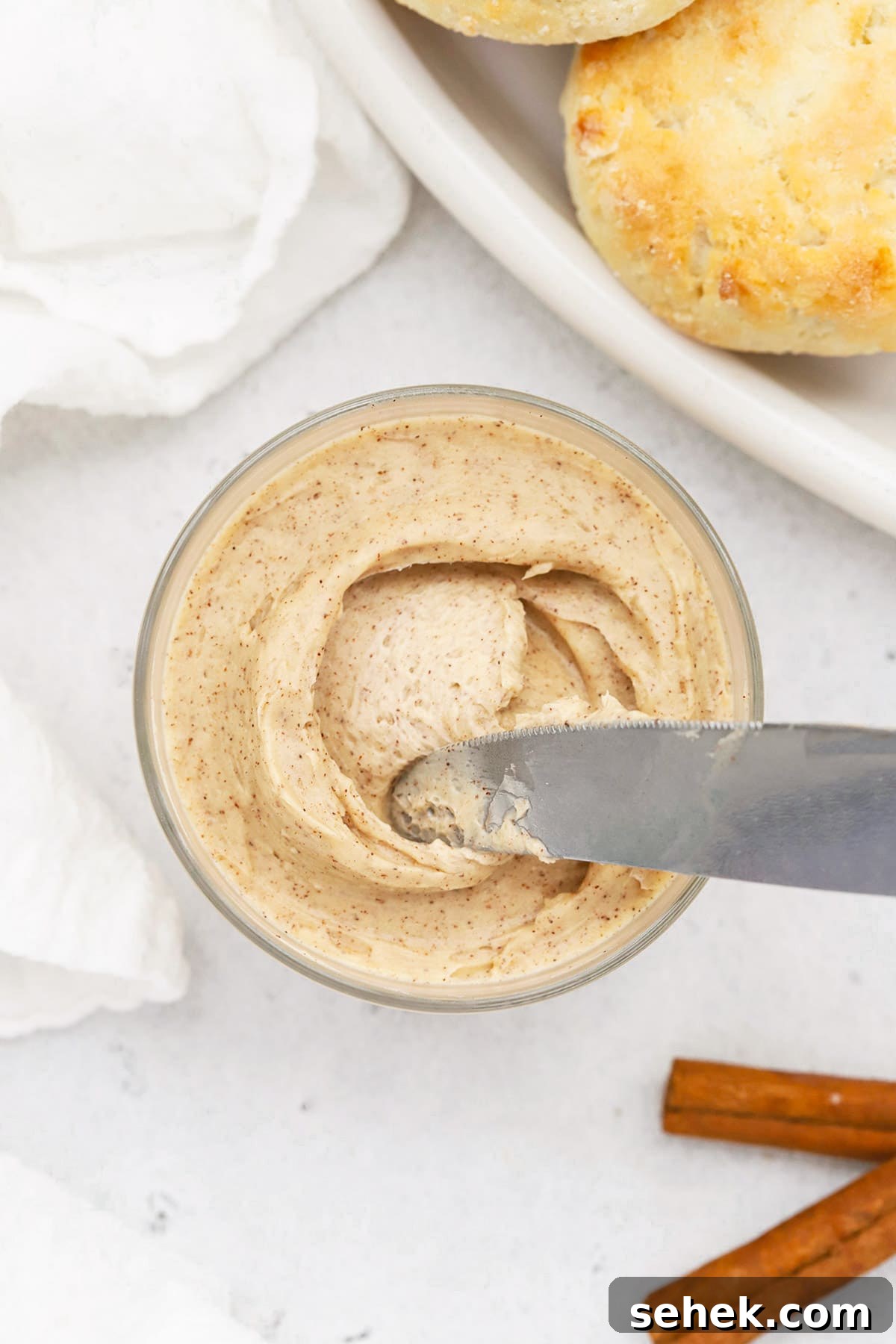 Whipped Honey Butter with Cinnamon — Fluffy Spread Recipe 14 Overhead view of whipped honey butter in a small glass jar with gluten-free biscuits in the background