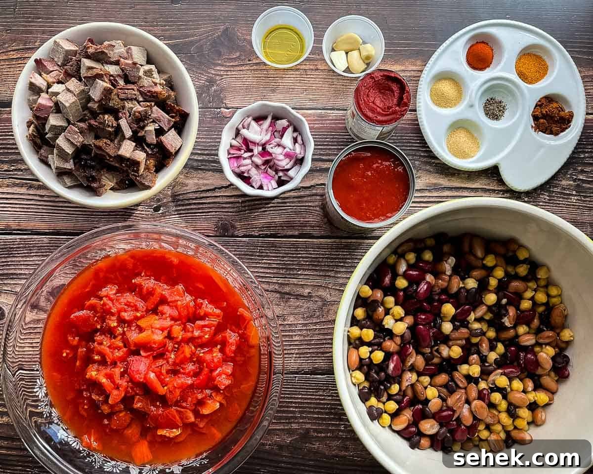 Smoked Brisket and Bean Chili Recipe for Flavorful Comfort 4 Ingredients for smoked brisket chili including leftover smoked brisket, mixed beans, tomatoes, tomato paste, red onion, garlic, and spices on a wooden table.