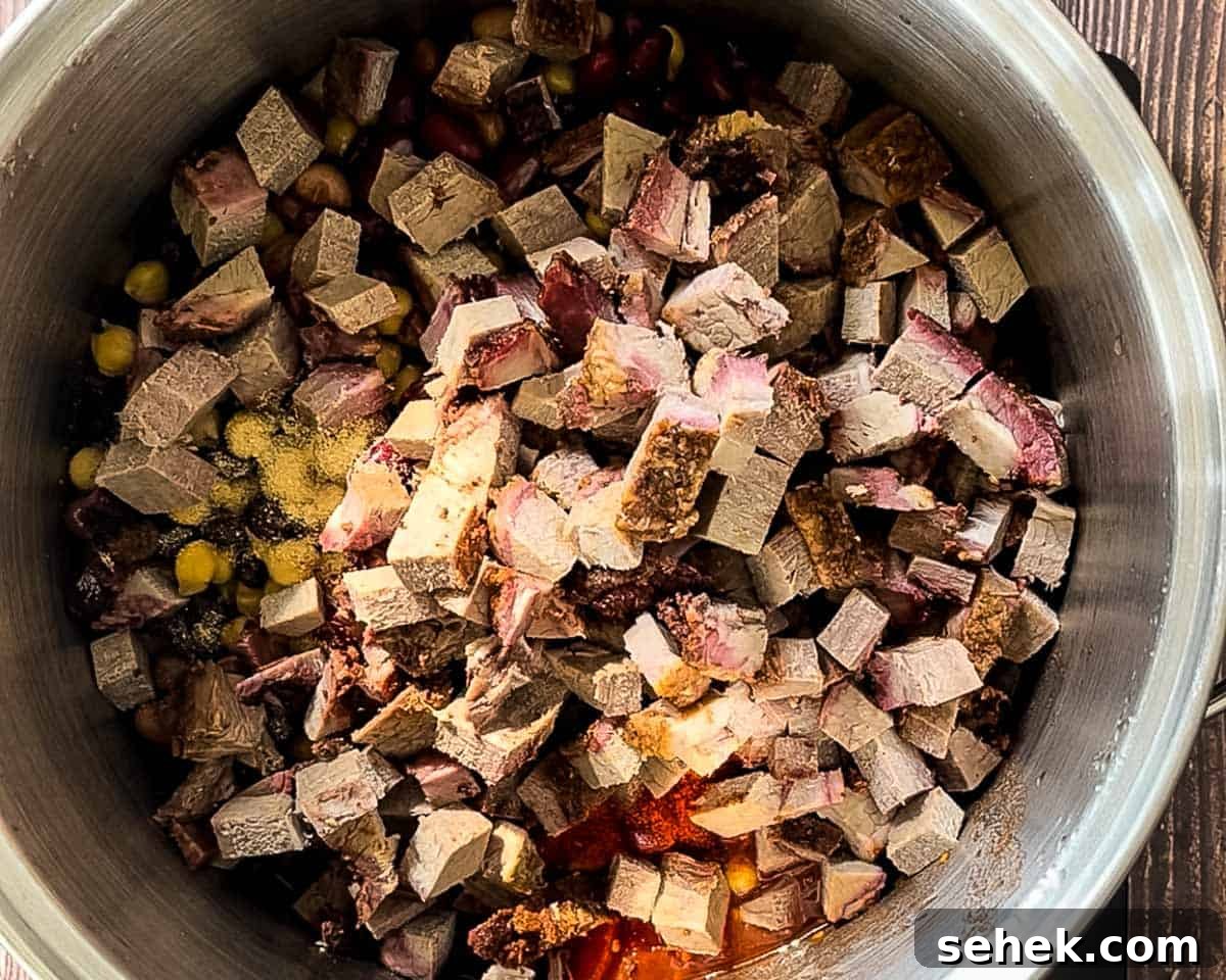 Smoked Brisket and Bean Chili Recipe for Flavorful Comfort 6 Cubed smoked brisket added to a pot with beans, tomatoes, and spices.