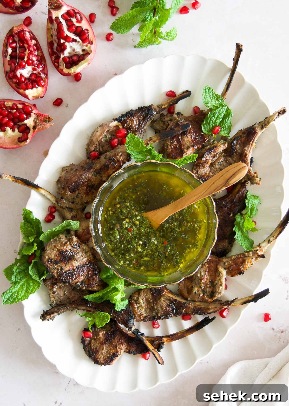 Marinated Grilled Lamb Chops Recipe for Juicy, Flavorful Results 2 grilled chimichurri lamb chops on a platter with a bowl more chimi in the middle and pomegranates
