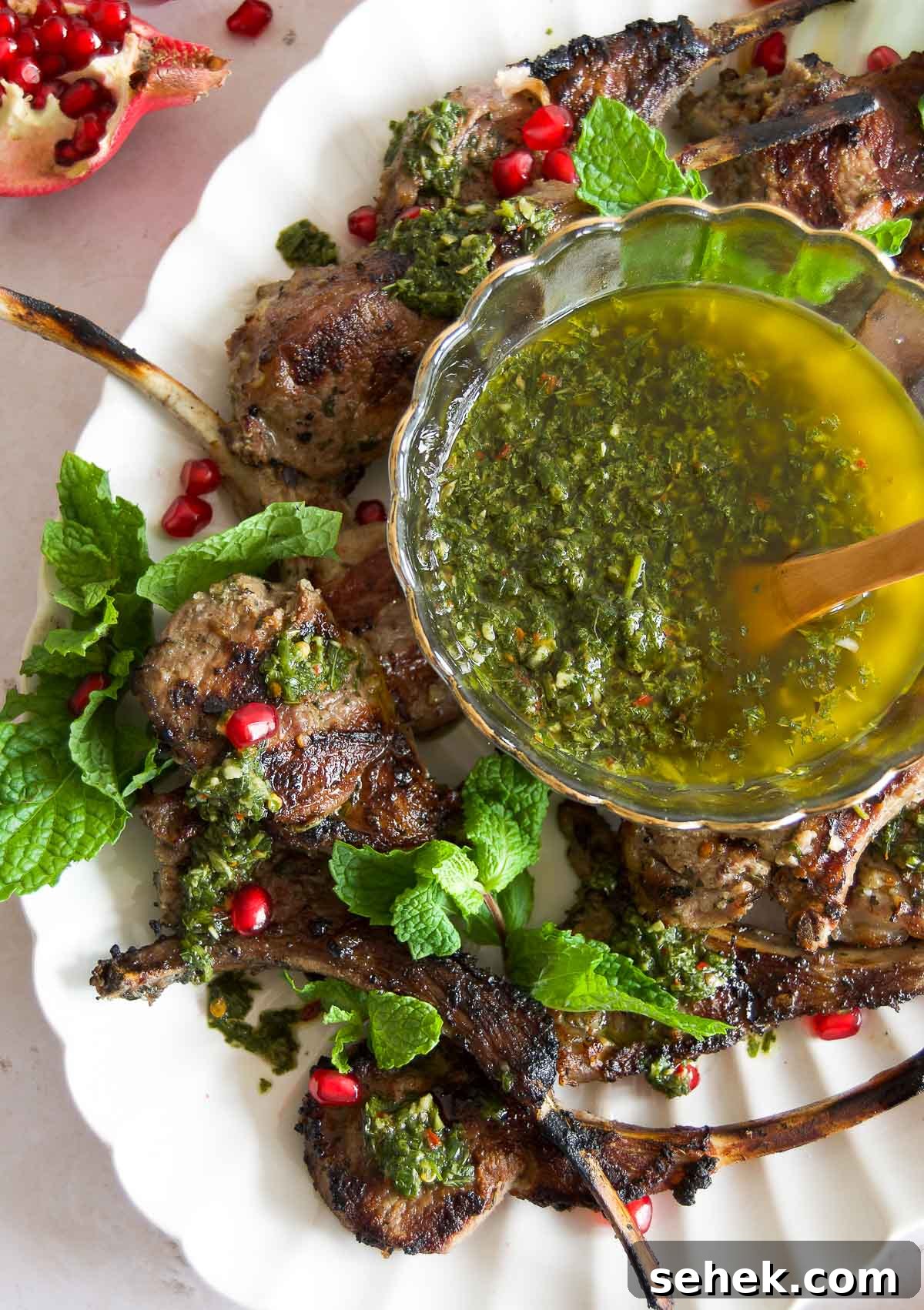 Marinated Grilled Lamb Chops Recipe for Juicy, Flavorful Results 8 close up of grilled lamb chops topped with chimichurri, fresh mint leaves and pomegranate seeds on a platter