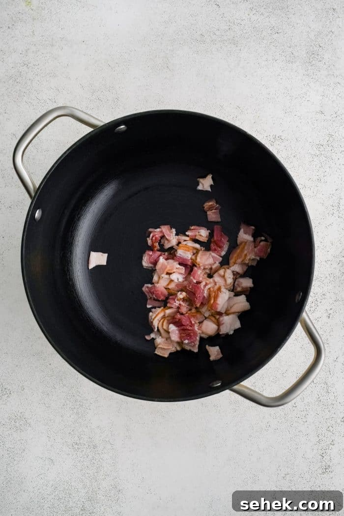 Large soup pot with a small pile of raw chopped bacon.
