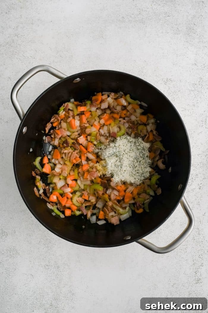 Dry ranch seasoning and garlic added to a large pot filled with carrots, onions, and celery sautéeing in butter.