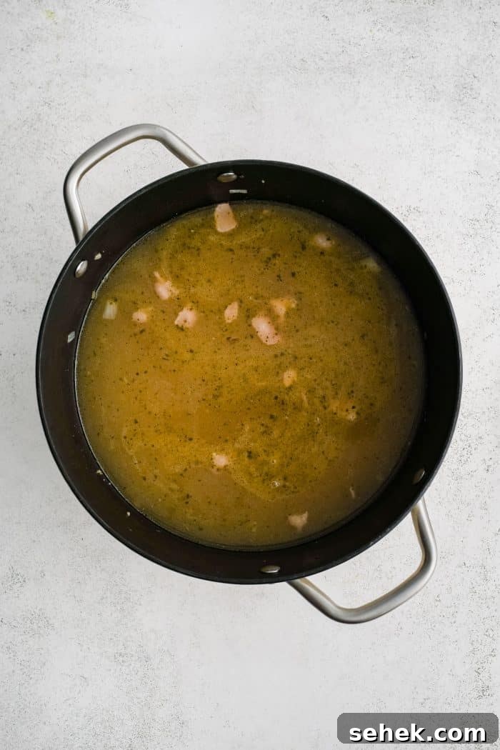 Large soup pot filled with simmering pasta, bacon. and veggies in ranch-seasoned broth.