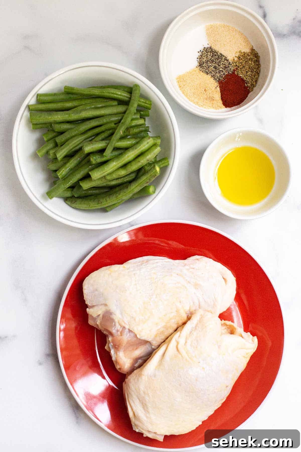 Ingredients for baked chicken thighs and green beans sheet pan dinner: raw bone-in skin-on chicken thighs, olive oil, seasoning, and raw green beans.