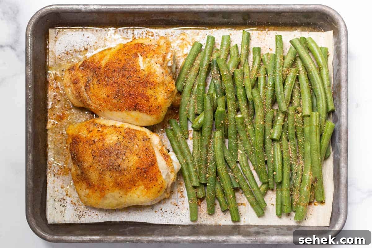 Partially cooked chicken thighs with uncooked and seasoned green beans with the ends trimmed.